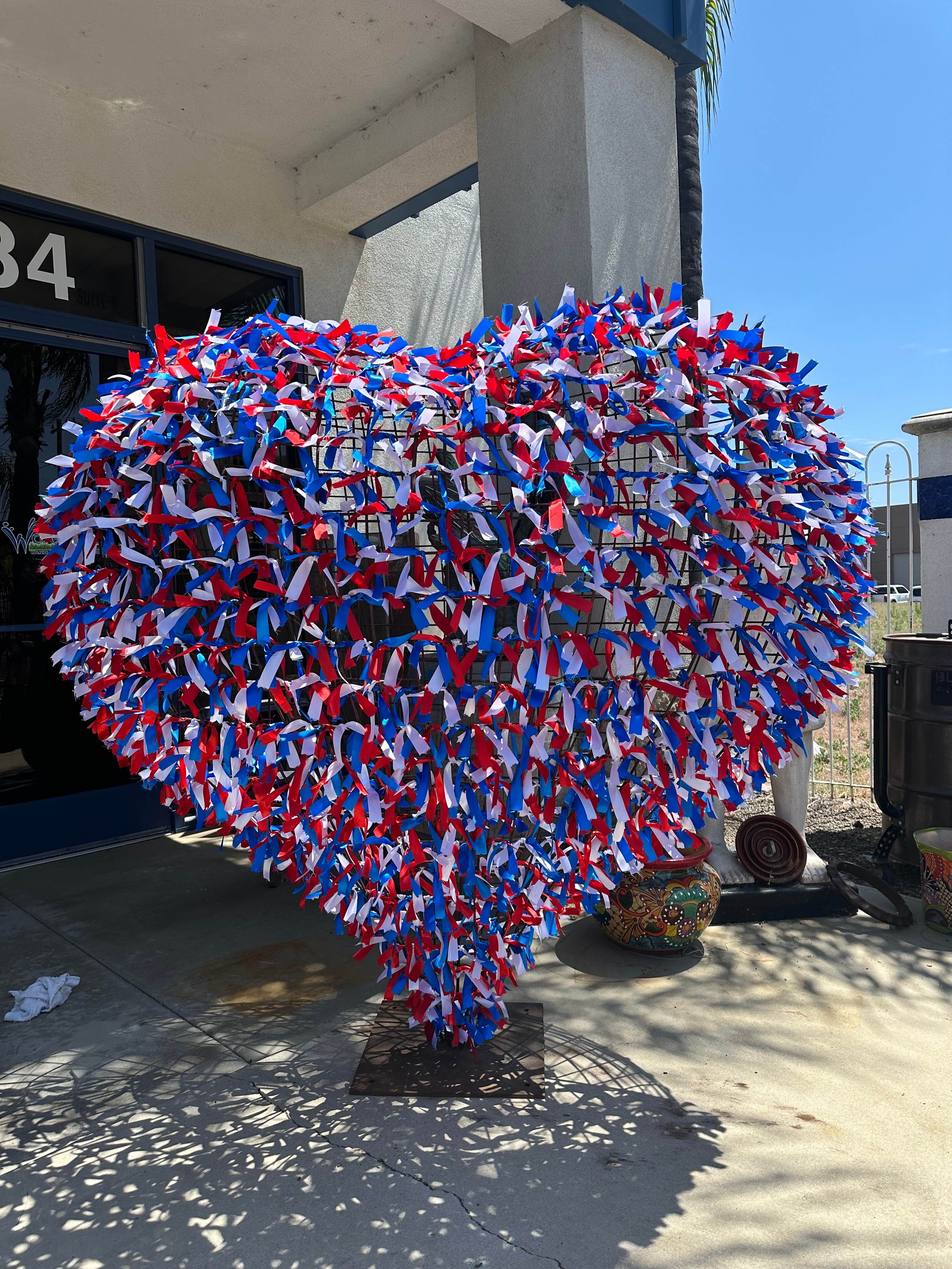 Giant steel heart wrapped in red, white and blue ribbons outside the showroom