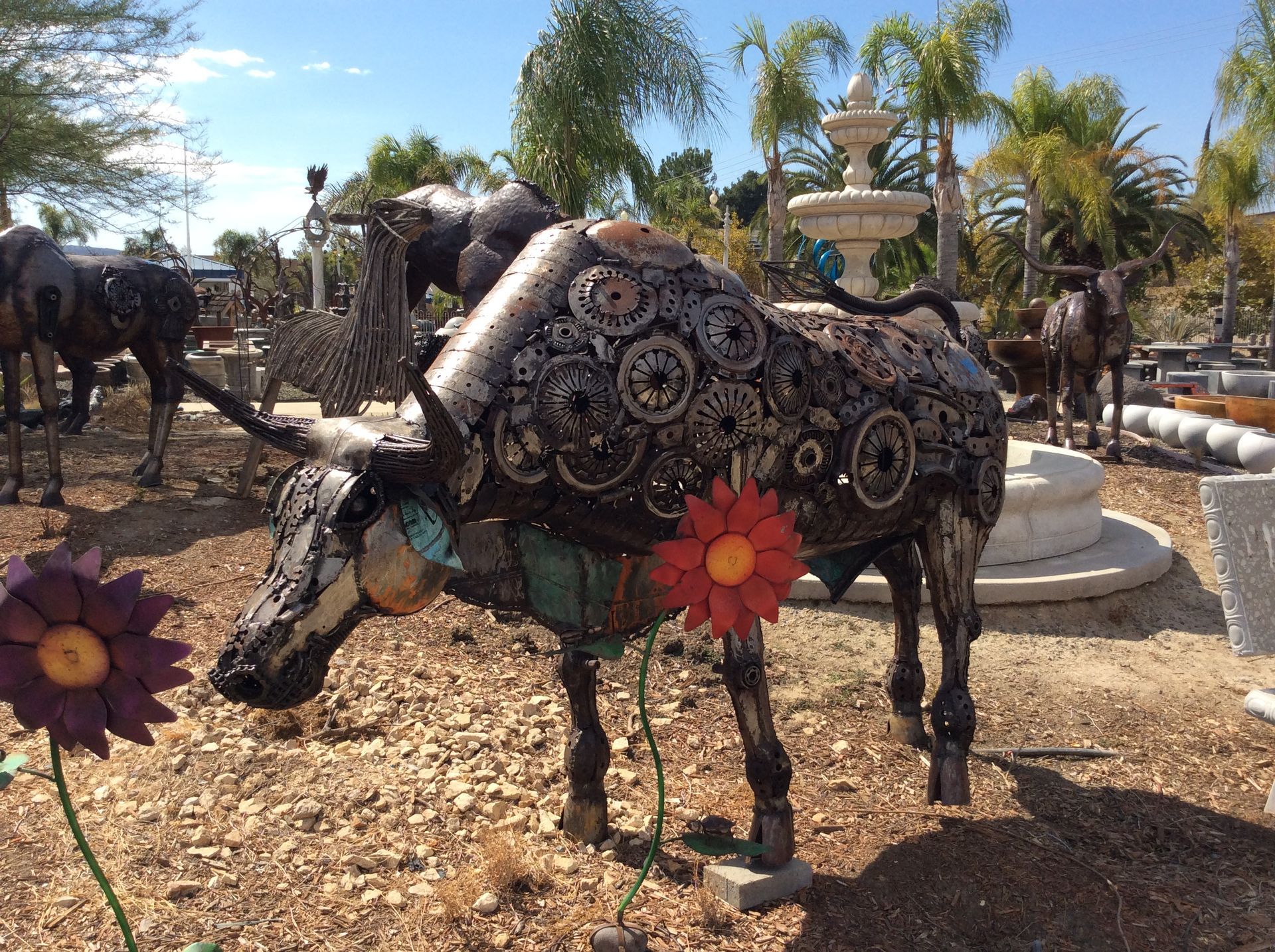 Recycled metal cow sculpture with a steel flower